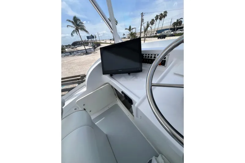 Slide: The Image of 1973 Bertram 31 Flybridge Cruiser helm with steering wheel and monitor, palm trees in background. - 33