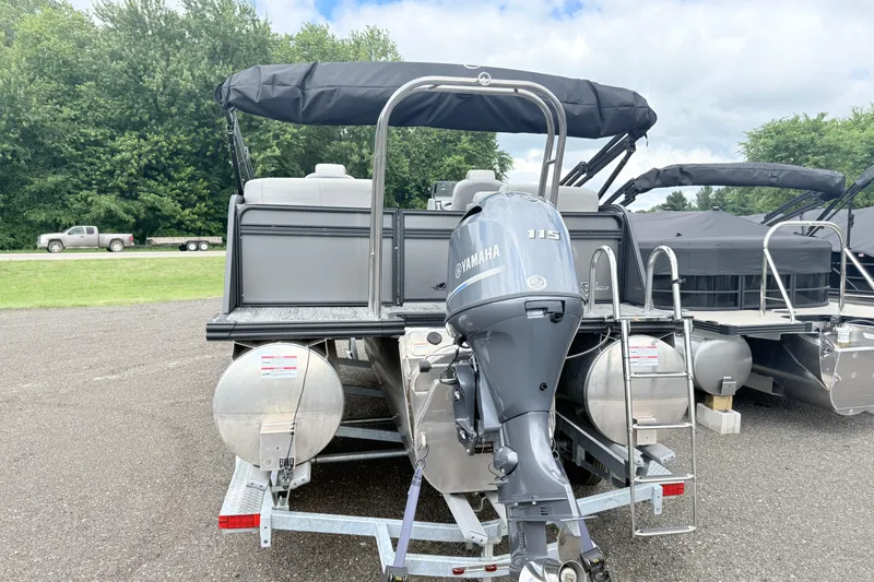 Slide: The Image of 2026 Qwest E-Class RLS 18 pontoon boat with Yamaha 115 engine, parked outdoors. - 2