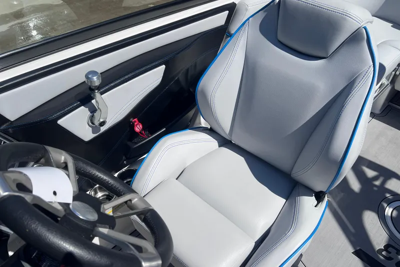 Slide: The Image of 2021 MasterCraft XT23 boat interior with sleek steering wheel and comfortable seating. - 14