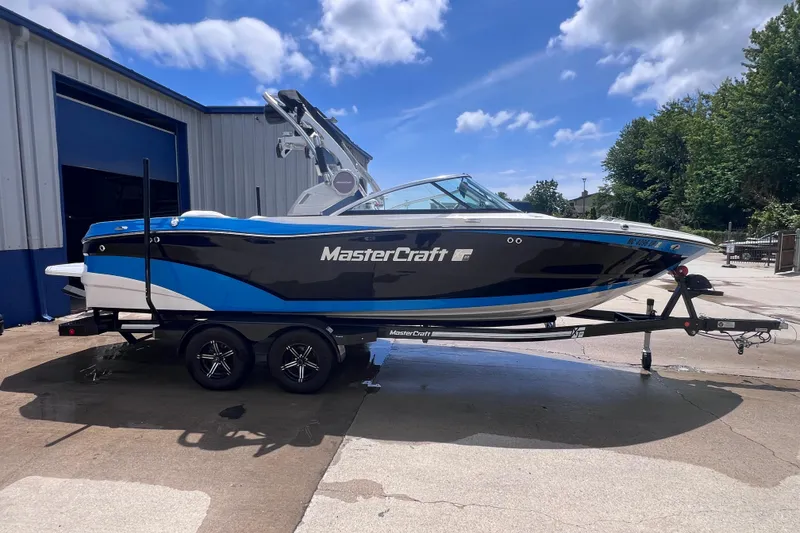 Slide: The Image of 2021 MasterCraft XT23 boat on trailer, parked outside a building under a blue sky. - 3