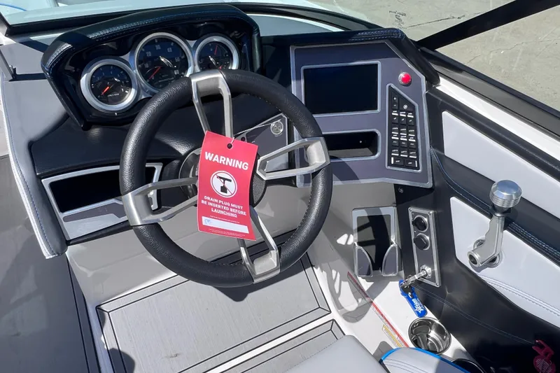 Slide: The Image of 2021 MasterCraft XT23 boat dashboard with steering wheel, warning tag, and control panel. - 16