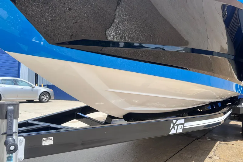 Slide: The Image of 2021 MasterCraft XT23 boat on trailer, showcasing sleek hull design and vibrant blue accents. - 8