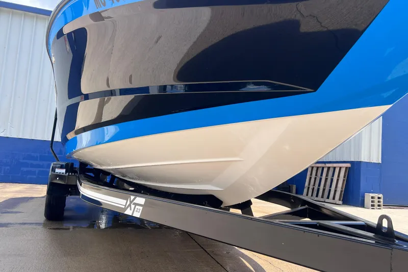 Slide: The Image of 2021 MasterCraft XT23 boat on trailer, blue and white hull, parked outdoors. - 7