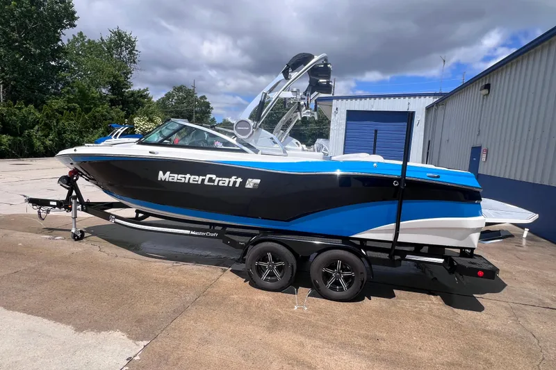 Slide: The Image of 2021 MasterCraft XT23 boat on trailer, parked outdoors near a building. - 1