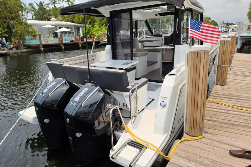Slide: The Image of 2025 Jeanneau NC 895 Series 2 boat docked with dual outboard engines and American flag. - 11