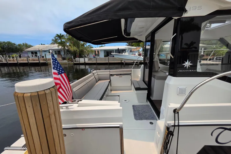 Slide: The Image of 2025 Jeanneau NC 895 Series 2 boat docked, featuring spacious seating and American flag. - 14