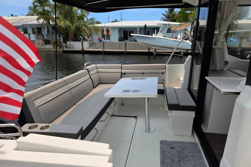 Slide: The Image of 2025 Jeanneau NC 895 Series 2 boat interior with seating and table, docked by waterfront homes. - 15