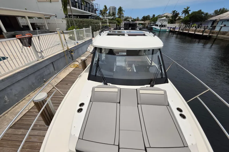 Slide: The Image of 2025 Jeanneau NC 895 Series 2 boat docked by a canal, featuring spacious deck seating. - 20