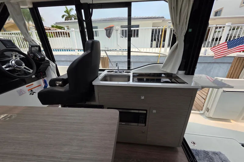 Slide: The Image of Interior of 2025 Jeanneau NC 895 Series 2 boat with helm, kitchenette, and American flag. - 27