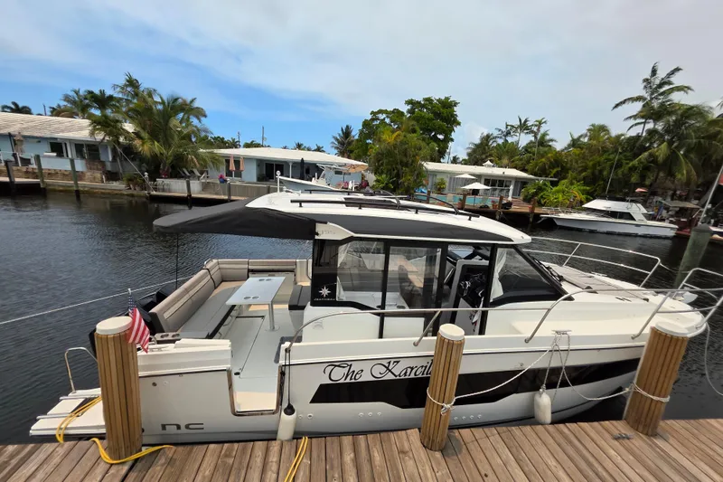 The Image of 2025 Jeanneau NC 895 Series 2 docked by waterfront homes, featuring sleek design and spacious deck. - 9