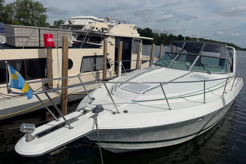 Slide: The Image of 1999 Formula 34 Performance Cruiser docked beside a houseboat on a calm river. - 2