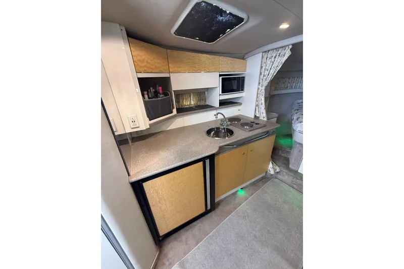 Slide: The Image of 1999 Formula 34 Performance Cruiser kitchen with sink, stove, microwave, and storage cabinets. - 23