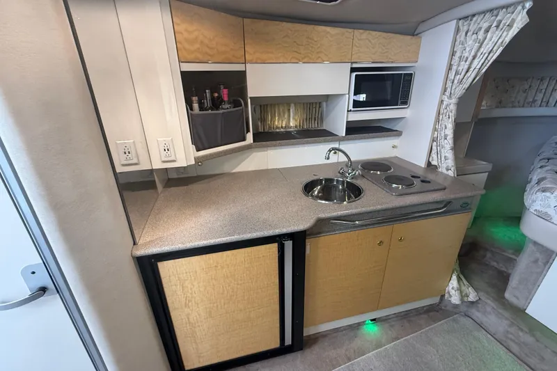 Slide: The Image of 1999 Formula 34 Performance Cruiser kitchen with sink, stove, microwave, and storage cabinets. - 24