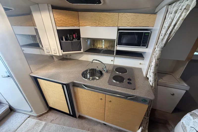 Slide: The Image of 1999 Formula 34 Performance Cruiser kitchen with sink, stove, microwave, and storage cabinets. - 27