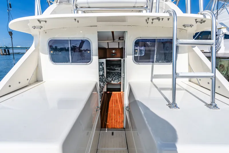 Slide: The Image of 1979 Bertram Flybridge Cruiser with open cabin and ladder, docked by the water. - 18