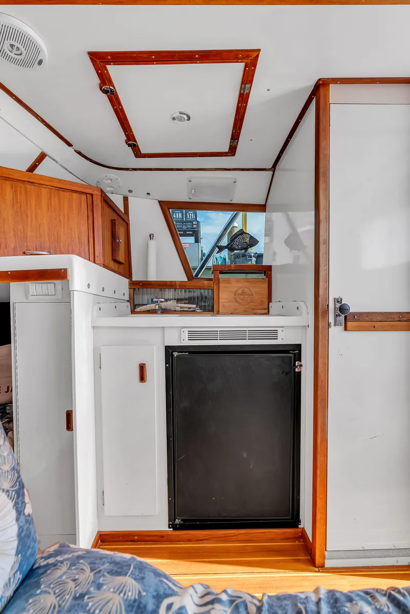 Slide: The Image of Interior of a 1979 Bertram Flybridge Cruiser with wood accents and a refrigerator. - 28