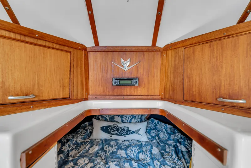 Slide: The Image of Interior of a 1979 Bertram Flybridge Cruiser with wooden cabinetry and a bed featuring a fish pillow. - 31