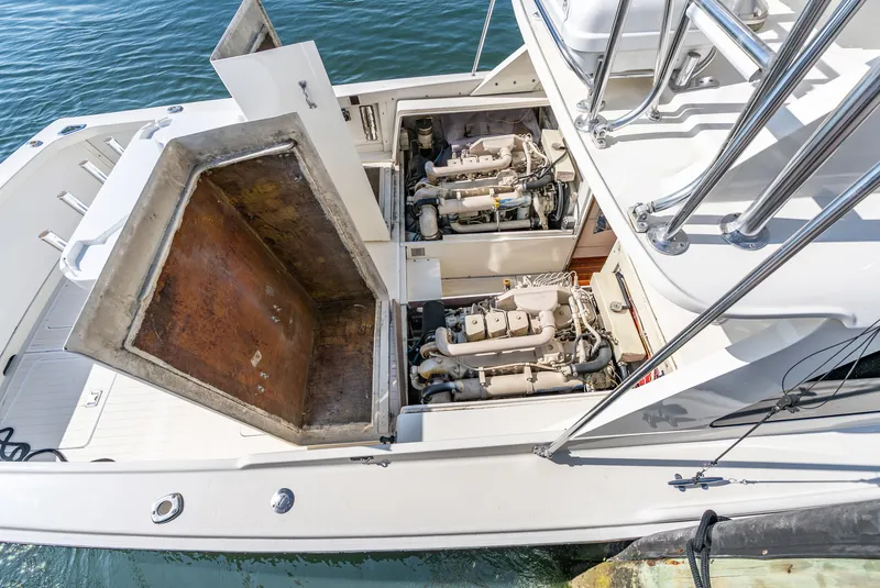 Slide: The Image of A 1979 Bertram Flybridge Cruiser with open engine compartments by the water. - 46