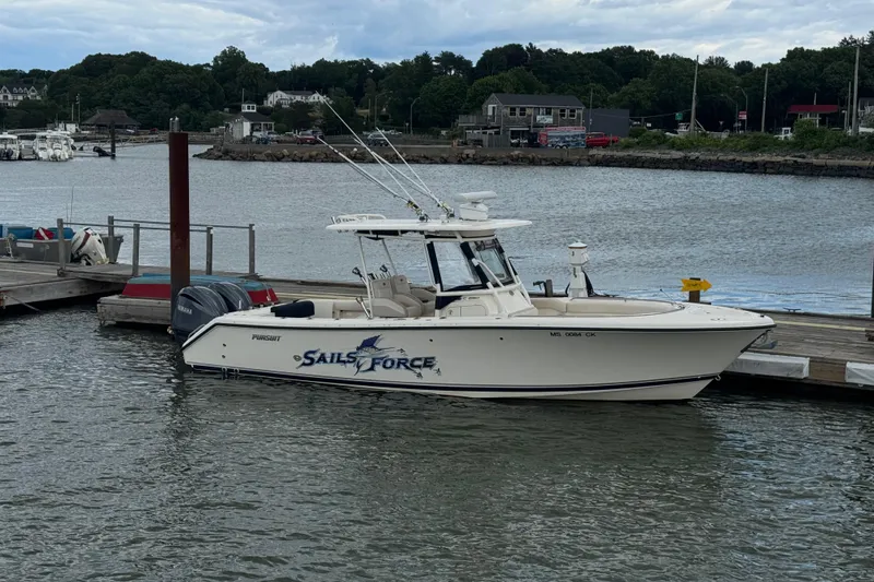 Slide: The Image of 2011 Pursuit boat "Sails Force" docked at a marina with scenic background. - 1
