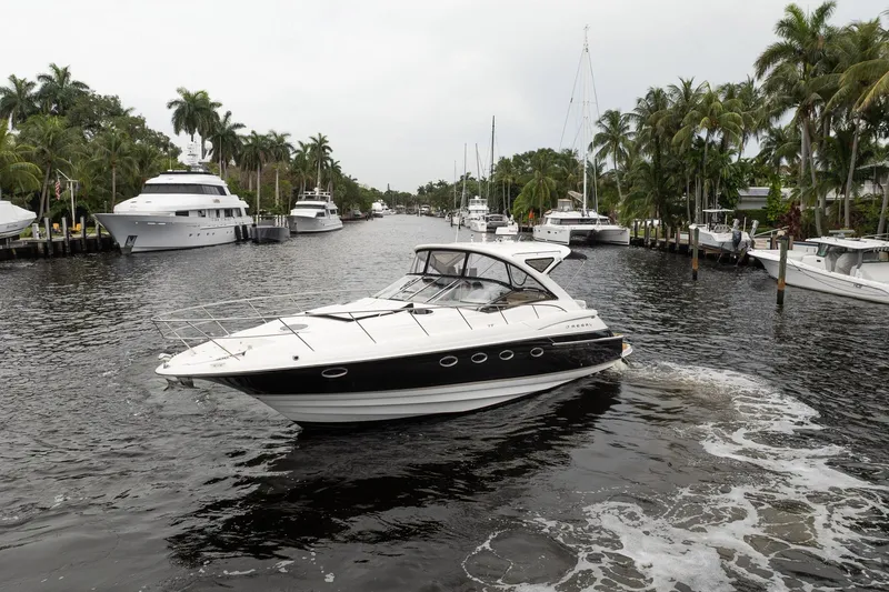 Slide: The Image of 2008 Regal Commodore 4460 yacht cruising in a scenic, palm-lined waterway. - 4
