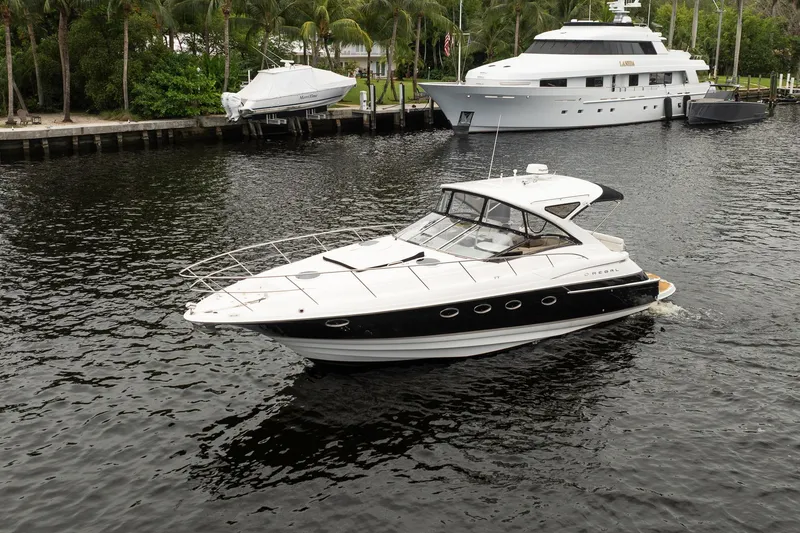 Slide: The Image of 2008 Regal Commodore 4460 yacht cruising on a serene waterway with palm trees in the background. - 21