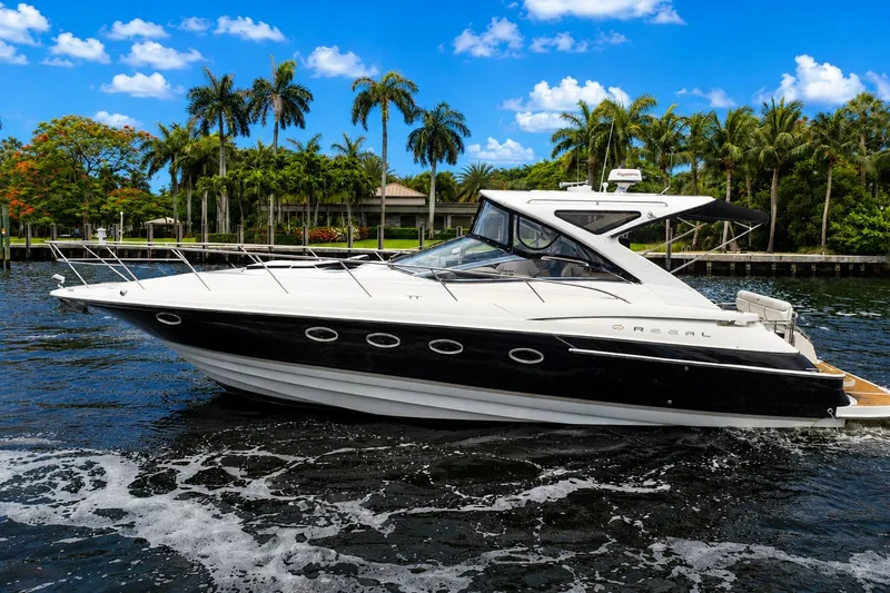 Slide: The Image of 2008 Regal Commodore 4460 yacht cruising on a scenic waterway with palm trees. - 1