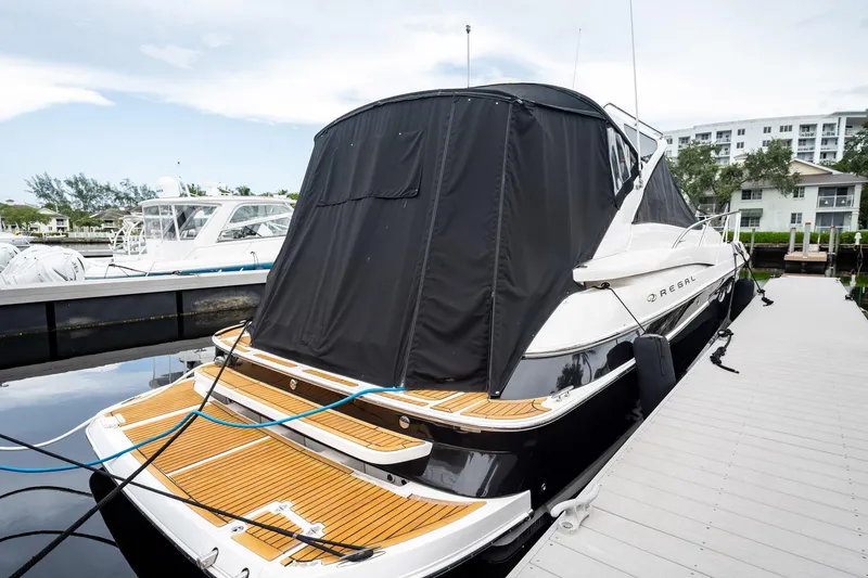 Slide: The Image of 2008 Regal Commodore 4460 yacht docked with black cover, wooden deck, and sleek design. - 26