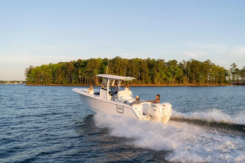 Slide: The Image of 2027 Sea Hunt Ultra 275 SE cruising on a scenic lake with lush green shoreline. - 1