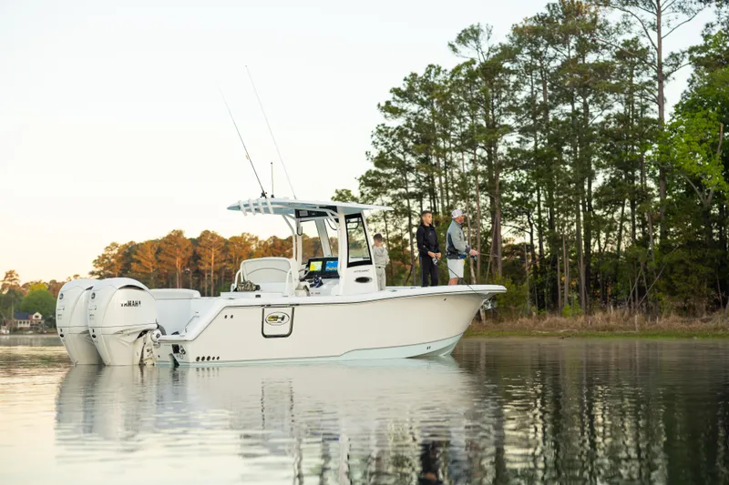 Slide: The Image of 2027 Sea Hunt Ultra 275 SE boat on calm water, people fishing, forested shoreline. - 0