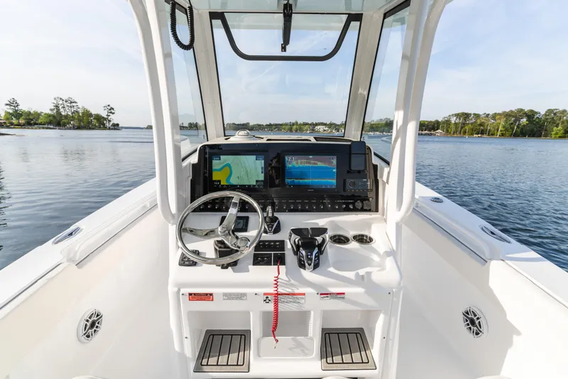 Slide: The Image of 2027 Sea Hunt Ultra 275 SE boat dashboard with navigation screens on a calm lake. - 16