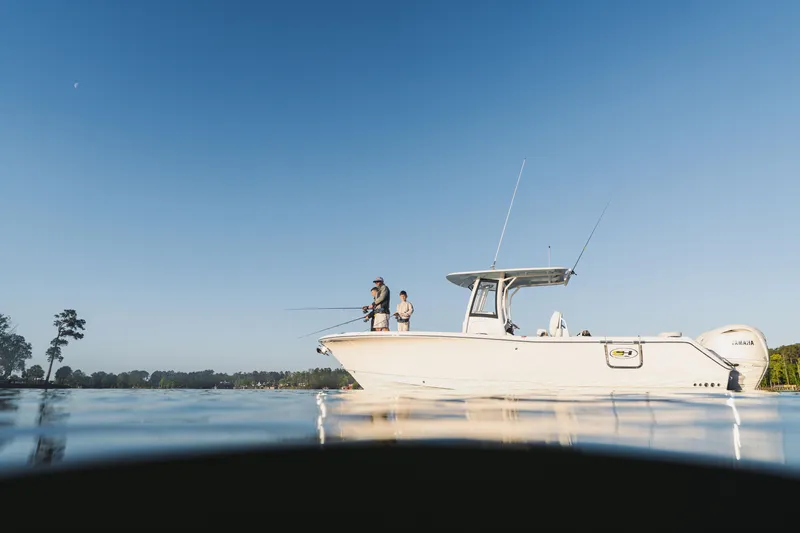 Slide: The Image of 2027 Sea Hunt Ultra 275 SE boat with anglers on calm water under clear sky. - 6