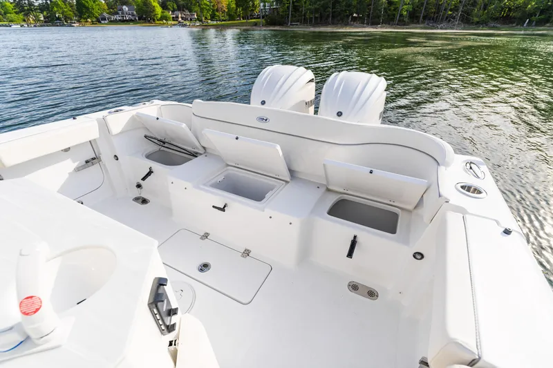 Slide: The Image of 2027 Sea Hunt Ultra 275 SE boat with open storage compartments on a calm lake. - 25