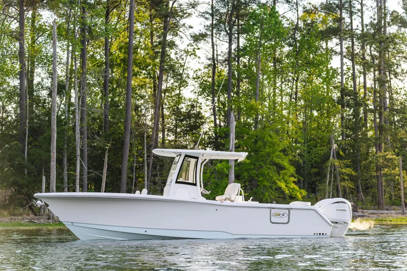 Slide: The Image of 2027 Sea Hunt Ultra 275 SE boat on a serene lake with forest backdrop. - 8