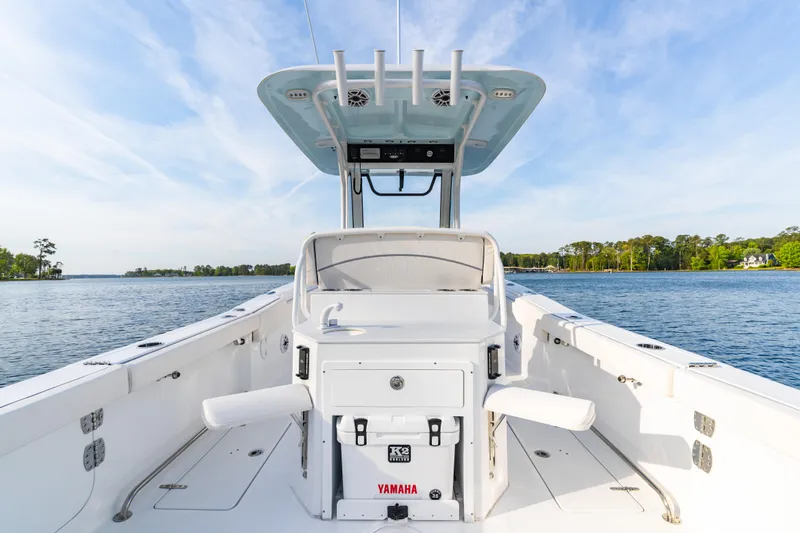 Slide: The Image of 2027 Sea Hunt Ultra 275 SE boat on calm water, showcasing spacious deck and helm. - 18