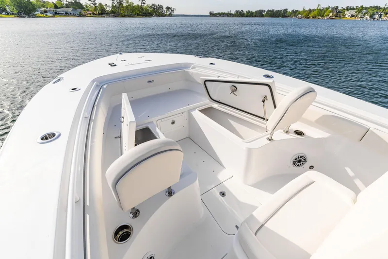 Slide: The Image of 2027 Sea Hunt Ultra 275 SE boat interior with open storage compartments on a calm lake. - 26