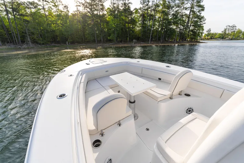 Slide: The Image of 2027 Sea Hunt Ultra 275 SE boat interior with seating and table on calm water. - 11