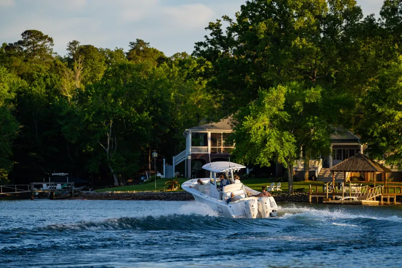 Slide: The Image of Sea Hunt Ultra 275 SE boat cruising on a scenic lake near waterfront homes, 2027 model. - 30