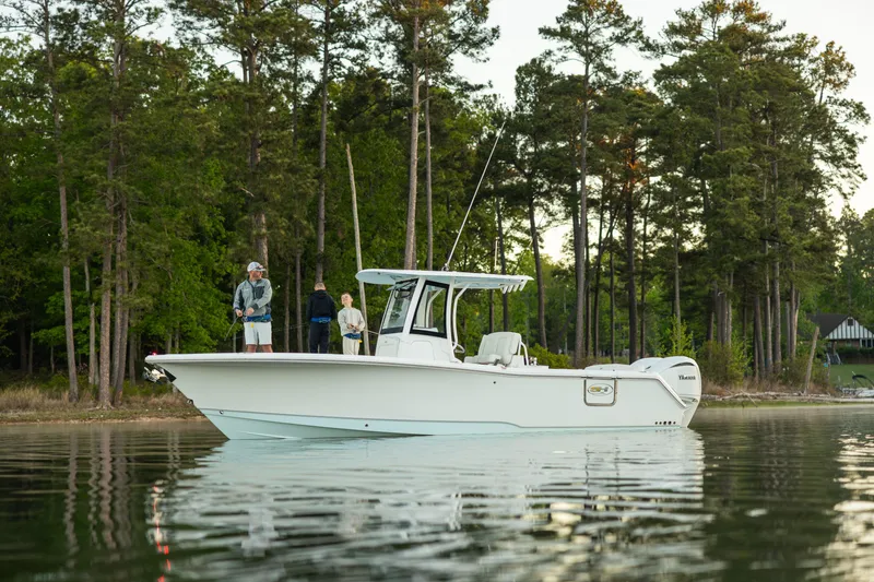 Slide: The Image of 2027 Sea Hunt Ultra 275 SE boat on calm lake near forested shoreline. - 32