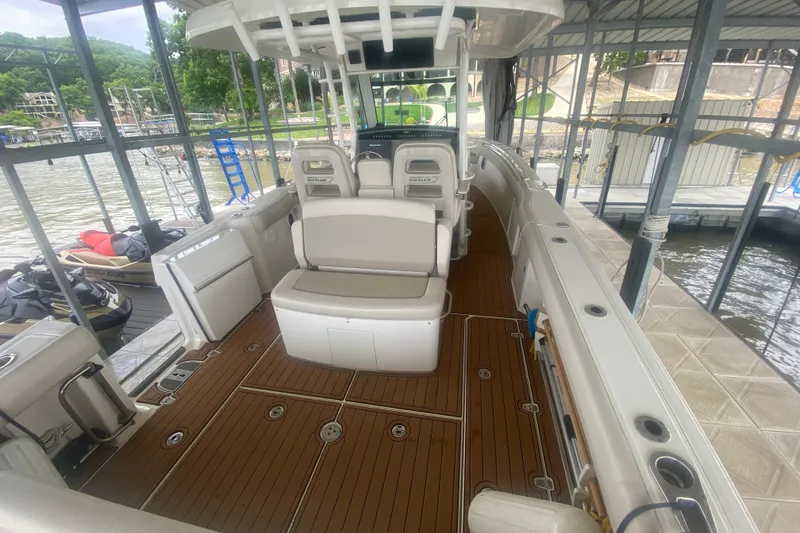 Slide: The Image of 2016 Boston Whaler 330 Outrage boat interior with seating and wood flooring at a dock. - 27