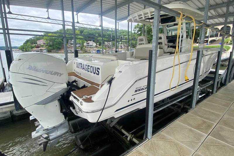 Slide: The Image of 2016 Boston Whaler 330 Outrage boat docked with Mercury engine, scenic waterfront background. - 8