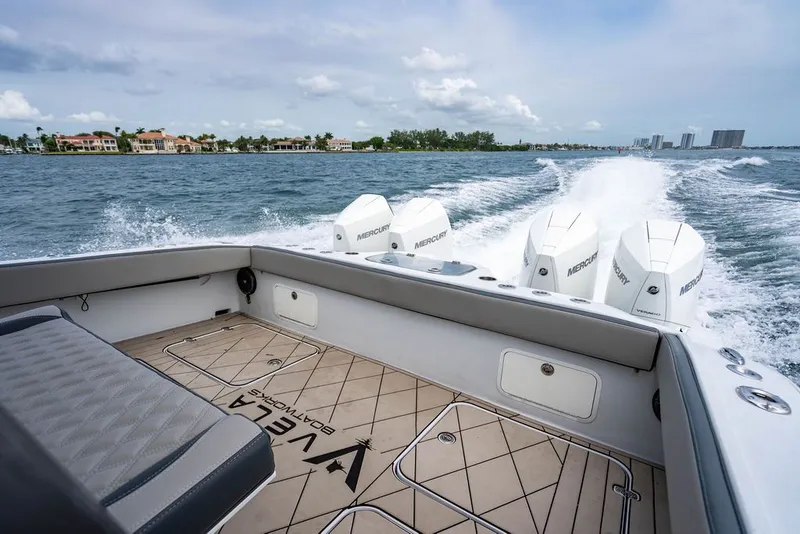 Slide: The Image of Boat with four outboard engines on the water, with a view of the shoreline and buildings in the background. - 37