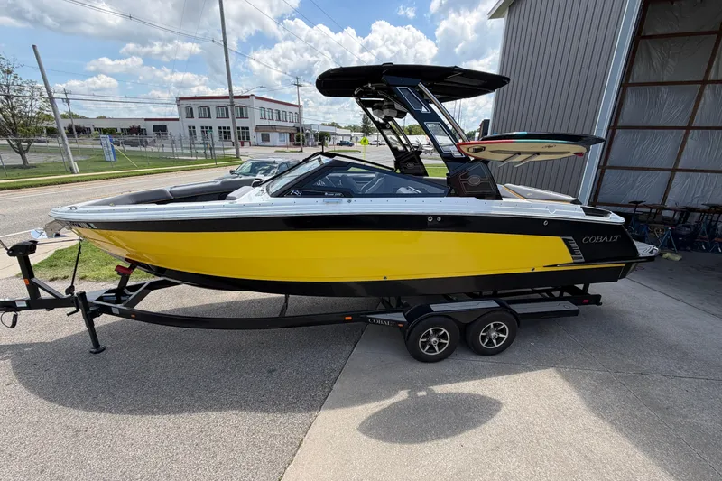 The Image of 2021 Cobalt R8 Surf boat in vibrant yellow on a trailer, parked outdoors. - 0