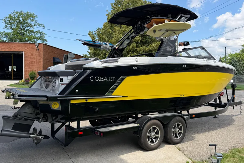 Slide: The Image of 2021 Cobalt R8 Surf boat in yellow and black on a trailer, parked outdoors. - 3