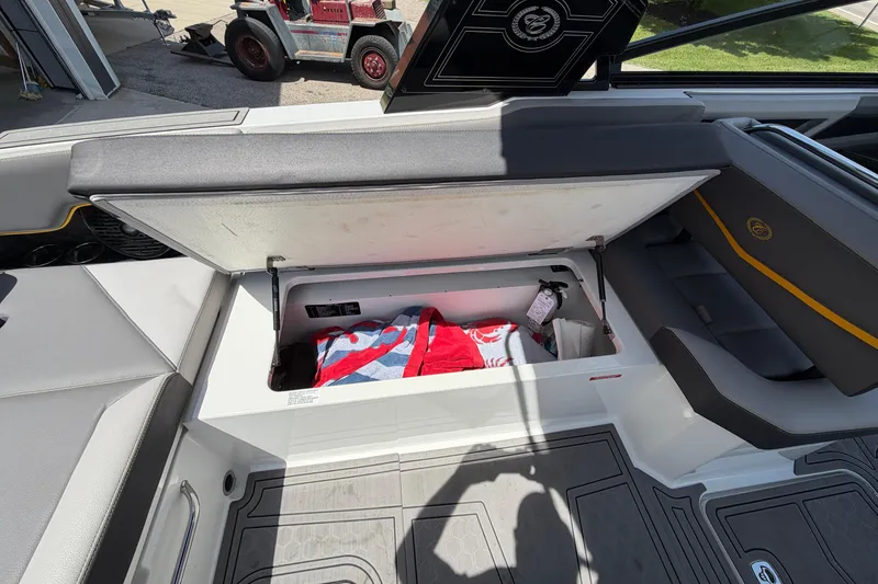 Slide: The Image of 2021 Cobalt R8 Surf boat interior storage compartment with open lid, revealing towels inside. - 9