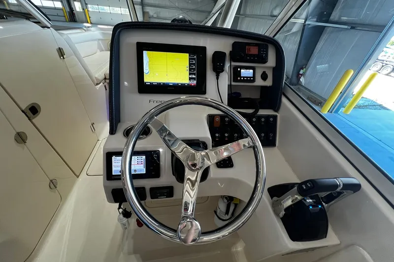 Slide: The Image of 2014 Grady-White Freedom 275 helm with steering wheel and navigation controls. - 12