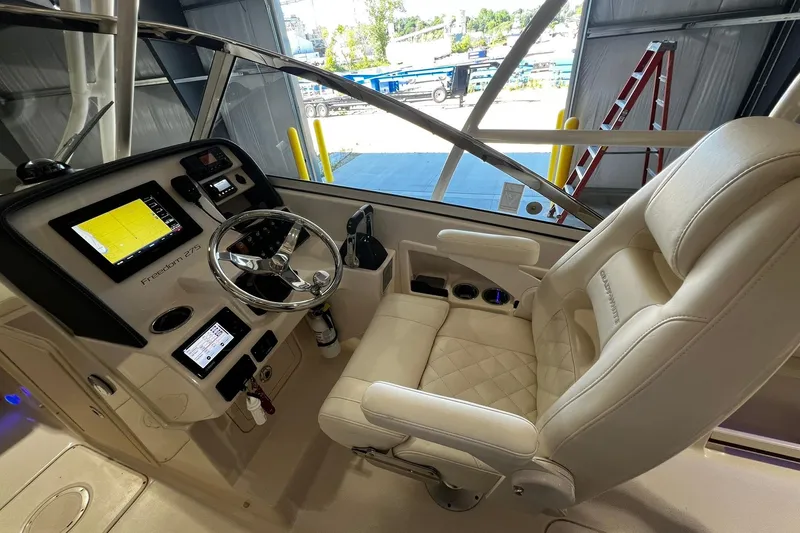 Slide: The Image of 2014 Grady-White Freedom 275 boat cockpit with steering wheel and navigation screens. - 17
