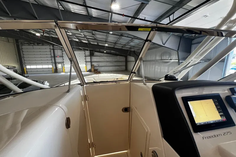 Slide: The Image of 2014 Grady-White Freedom 275 boat interior with navigation display in a spacious warehouse. - 9