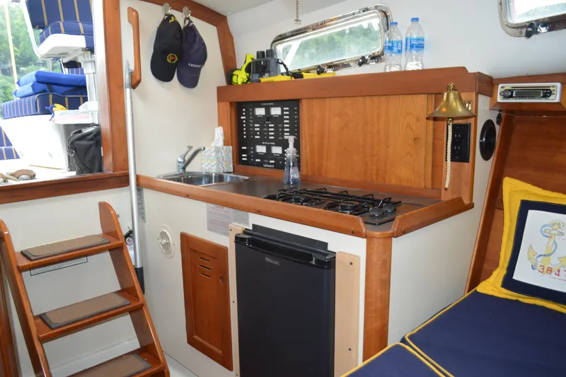 Slide: The Image of 2003 Legacy 28 Express boat interior with kitchenette, stove, sink, and nautical decor. - 8