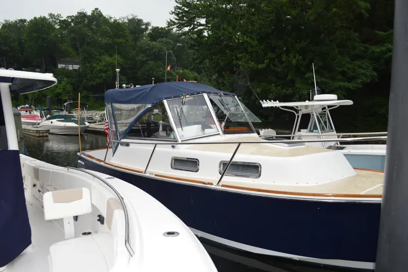 Slide: The Image of 2003 Legacy 28 Express boat docked in a marina, surrounded by lush greenery. - 2