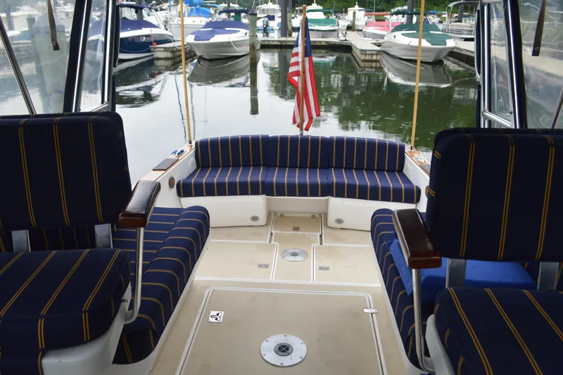 Slide: The Image of Interior view of a 2003 Legacy 28 Express boat with striped seating at a marina. - 6